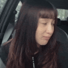 a woman is sitting in the driver 's seat of a car and laughing .