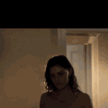 a naked woman is standing in a hallway looking at the camera .