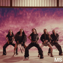 a group of women are dancing in front of a pink sky with the letters ms on the bottom right