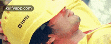 a man wearing a yellow hard hat is laying down with his head down .