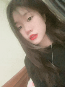 a girl with long black hair and red lipstick is looking at the camera