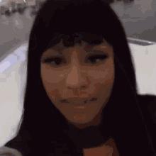 a close up of a woman 's face with long black hair and a fringe .