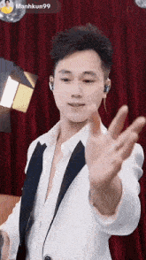 a man in a white suit is waving his hand