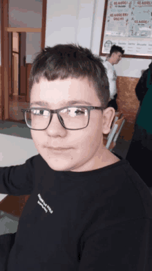 a young boy wearing glasses and a black shirt that says everybody loves a girl