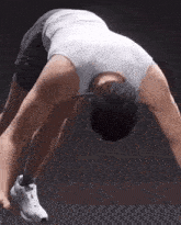 a man in a tank top and shorts is doing a handstand .