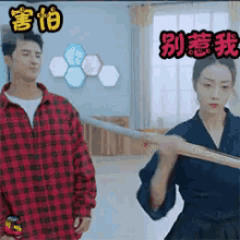 a man and a woman are standing next to each other in a room . the woman is holding a sword .