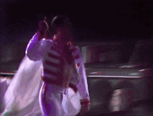 a man in a white and red suit is dancing on a stage