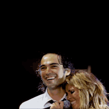 a woman singing into a microphone next to a man in a white shirt and tie