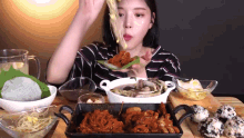 a woman is sitting at a table eating food from a pan