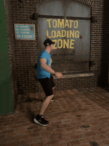 a man is standing in front of a tomato loading zone sign