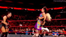 a group of women are wrestling in a ring with a crowd watching .