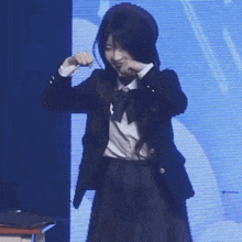 a girl in a school uniform is standing in front of a blue screen
