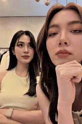 two women are sitting next to each other and one has her hand on her chin