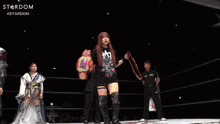a woman in a black shirt is holding a wrestling belt with the word stardom on it