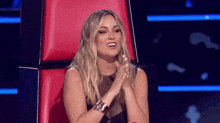 a woman is sitting in a red chair with her hands folded and smiling .