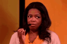 oprah winfrey is making a funny face while holding something in her hand .