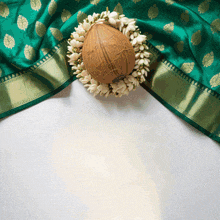 a coconut surrounded by white flowers sits on a green cloth