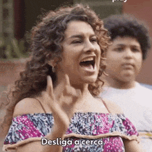 a woman with curly hair is screaming in spanish