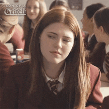 a girl in a school uniform is sitting in a classroom with her eyes closed