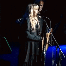 a man is playing a guitar and a woman is singing into a microphone on stage .