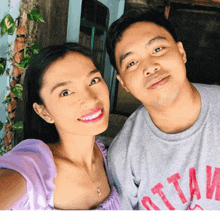 a man and a woman are posing for a picture and the man is wearing a gray shirt that says ottaw on it