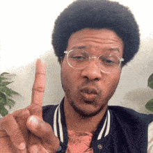 a man wearing glasses is blowing a kiss with his index finger