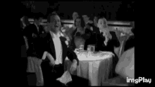 a group of men are sitting at a table clapping their hands .