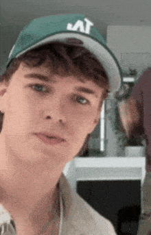 a young man wearing a green hat with the letter a on it .