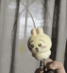 a person is holding a yellow bunny with a surprised face on it