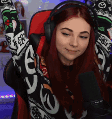 a woman wearing headphones and a sweater that says ' ve ' on it is sitting in front of a microphone