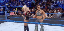 a couple of women are standing in a wrestling ring .