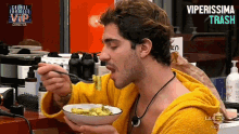 a man in a yellow robe is eating from a bowl with a spoon ..