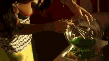 a woman is mixing green liquid in a bowl