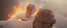 a man is being held by a statue with a fireball coming out of his chest