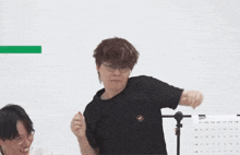 a man wearing glasses and a black shirt is standing in front of a calendar ..
