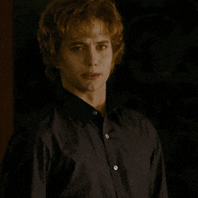 a man with red hair is wearing a black shirt with white buttons