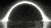 a black and white image of a black hole with a light coming out of it