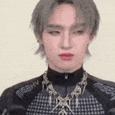 a close up of a young man wearing a necklace and earrings .