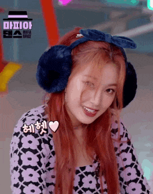 a girl with red hair wearing ear muffs and a bow in her hair .