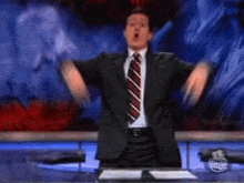 a man in a suit and tie is dancing in front of a news desk