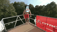 a man in red shorts is standing on a balcony with a citroen banner behind him