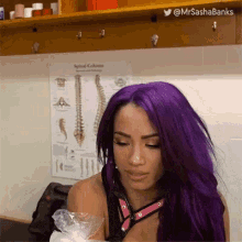 a woman with purple hair is standing in front of a poster of a spine .