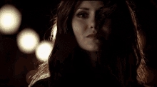 a close up of a woman 's face in a dark room with lights behind her .