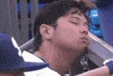 a man with his eyes closed is sitting in a stadium watching a baseball game