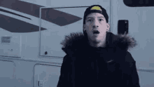 a man wearing a black jacket and a hat is standing in front of a rv .