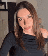 a woman with long brown hair is wearing a black top and making a funny face .