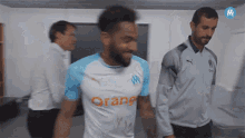 a man wearing an orange shirt stands in a locker room
