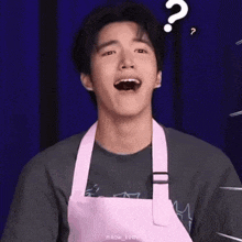 a young man wearing a pink apron is laughing with a question mark above his head .