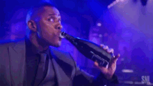 a man in a suit is drinking from a bottle that says snl