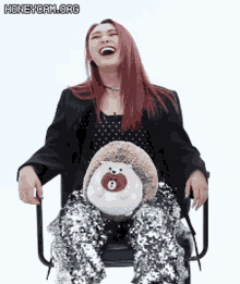 a woman is sitting in a chair holding a stuffed hedgehog